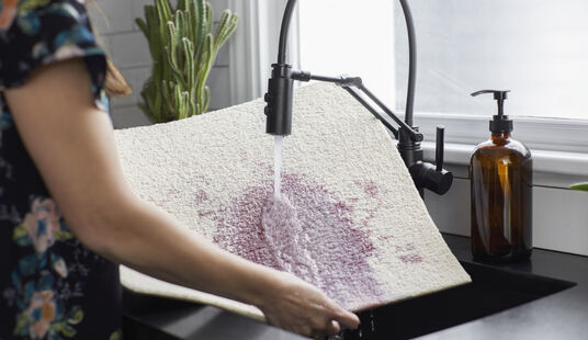 Photo showing carpet tile being cleaned in a sink